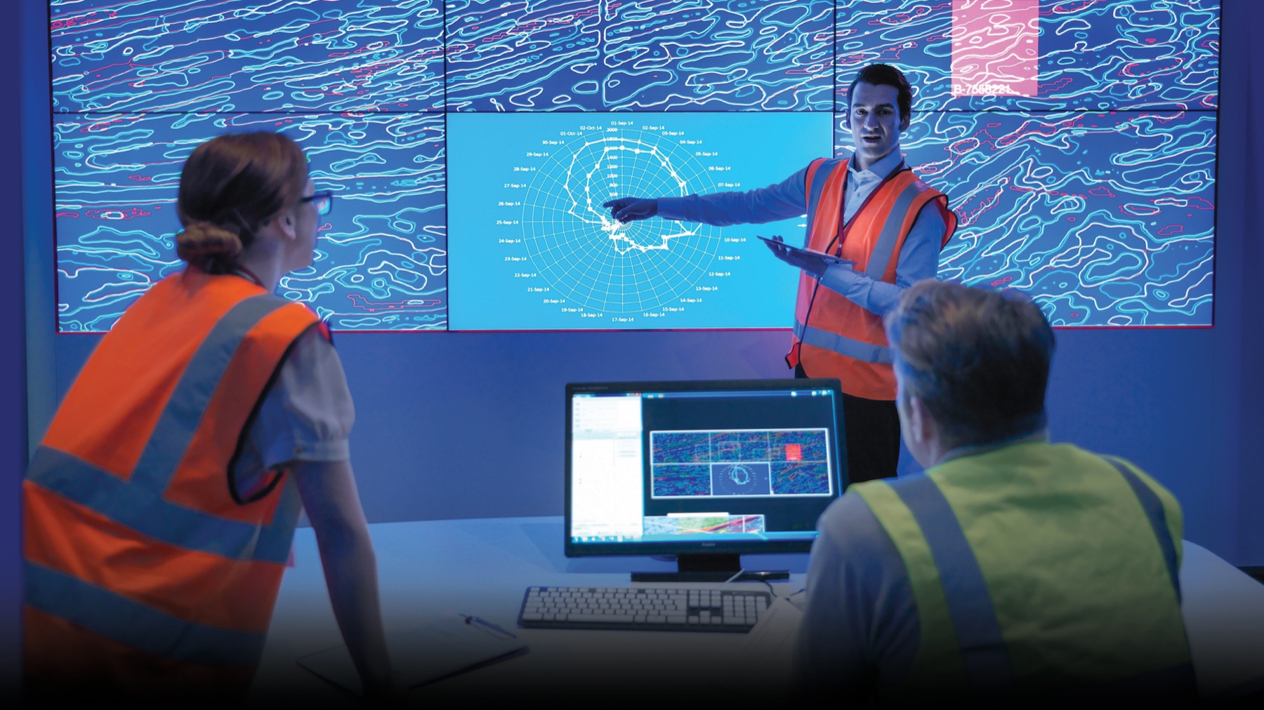 Geoscientists studying a large display of subsurface seismic data